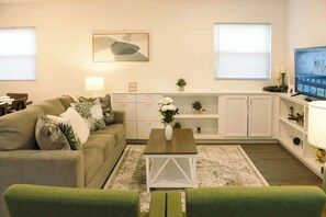 A living room with a sofa, a coffee table, a TV, and a cabinet. - Private Highlands Apt w/ Free Parking, Walk to (Louisville)