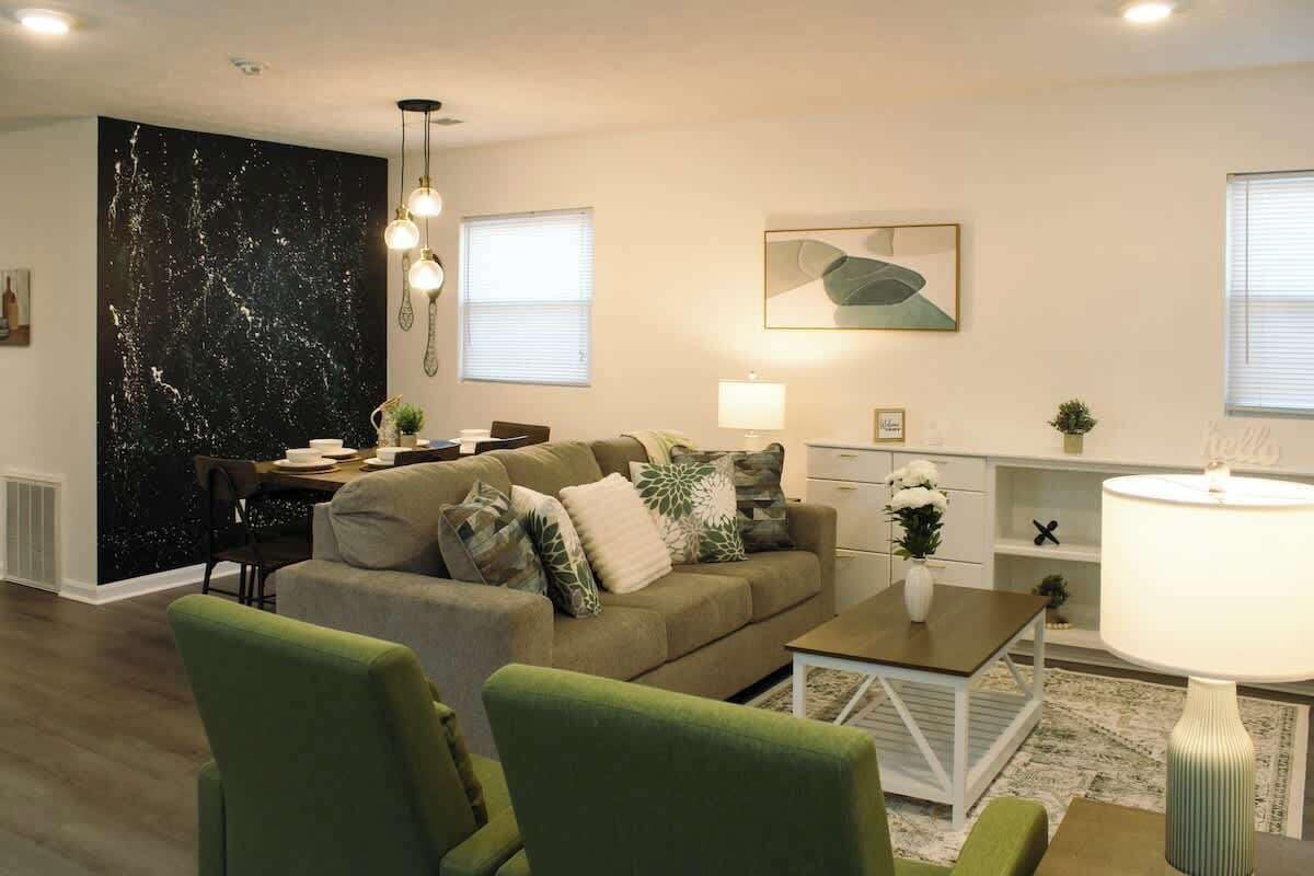 Ein modernes Wohnzimmer mit einer Couch, Sesseln, einem Couchtisch und einem Essbereich.