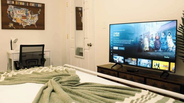 Ett hotellrum med en säng, ett skrivbord, en tv som visar ett program från Hulu och en väggkarta över USA.