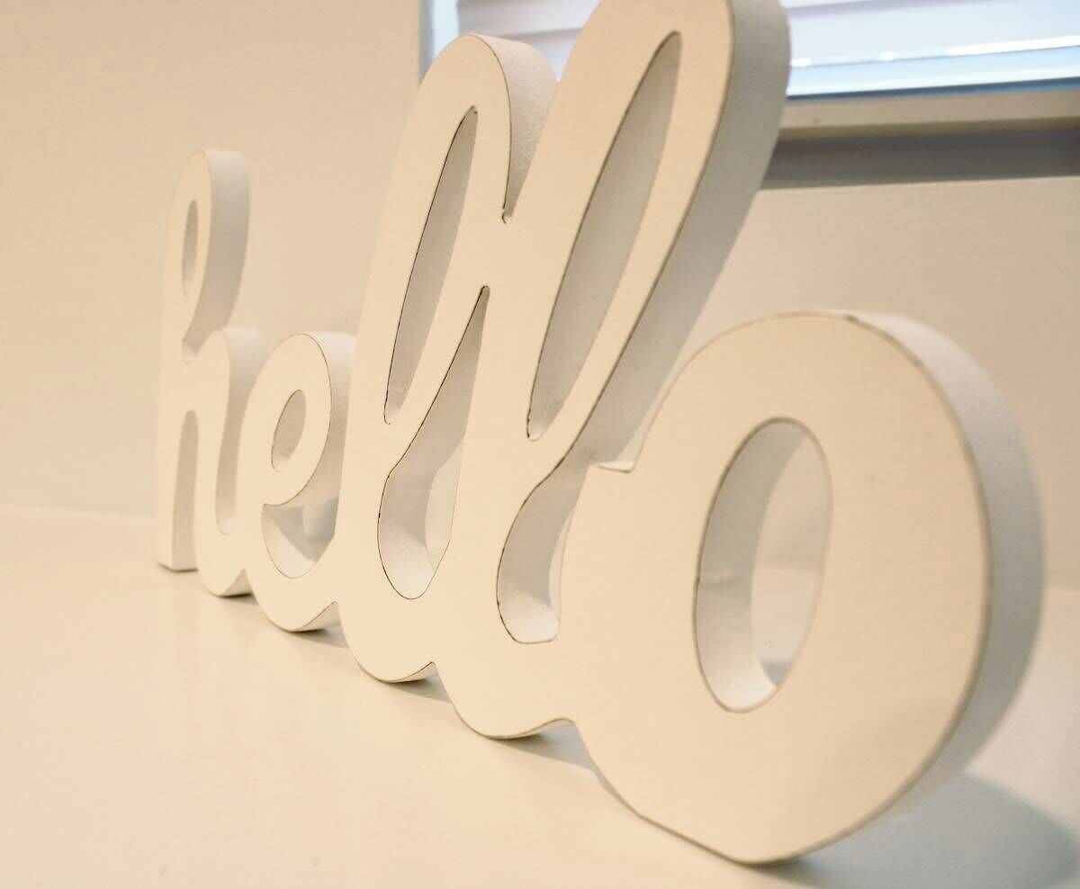 Ein weißes, dreidimensionales 'Hello'-Schild mit ausgeschnittenen Buchstaben.