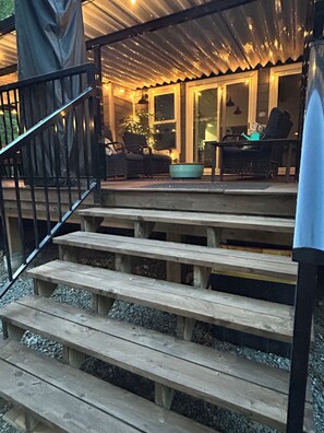 A wooden staircase leading to a covered outdoor area with seating and a table. - luxury ranch home in the mountains in Quad country near Manning Park ski resort. (Hope)