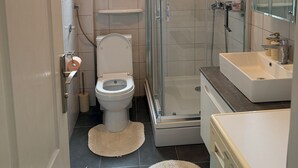 Un baño pequeño con inodoro, ducha y lavamanos.