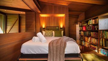 A wooden-paneled room with a bed, a bookshelf, and a wall-mounted light fixture.