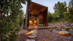 A modern house with a large open interior, a deck, and a fire feature.