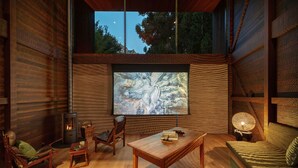 A cozy interior with a fireplace, comfortable seating, and a large window overlooking a natural landscape.