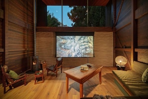 A cozy interior with a fireplace, comfortable seating, and a large window overlooking a natural landscape.