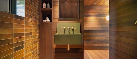 Un bagno con un lavandino verde, pannelli in legno e uno scaffale con articoli da toilette.