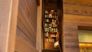 A staircase leading to a bookshelf filled with books, wooden walls, and a warm light source.