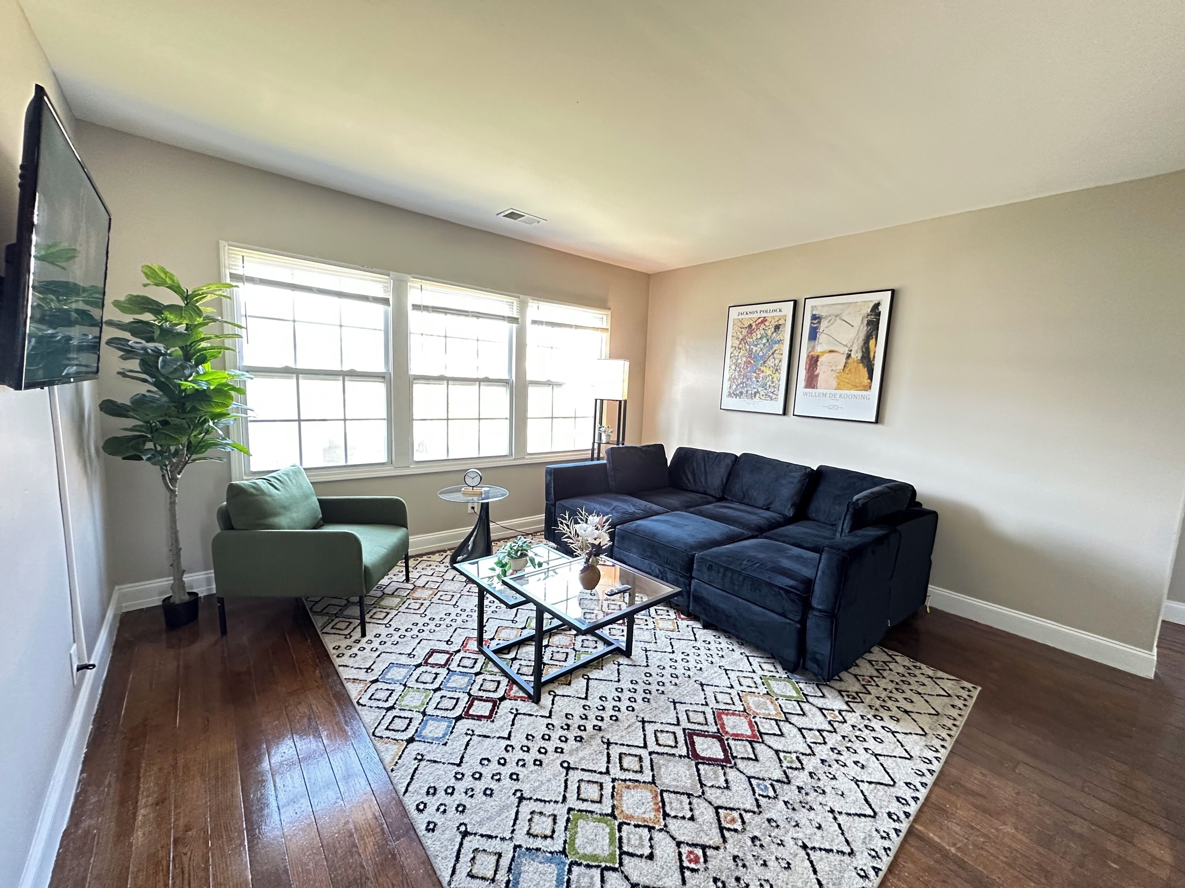 A living room with a sofa, armchair, coffee table, and a patterned rug.