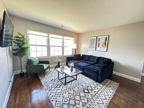 A living room with a sofa, armchair, coffee table, and a patterned rug.