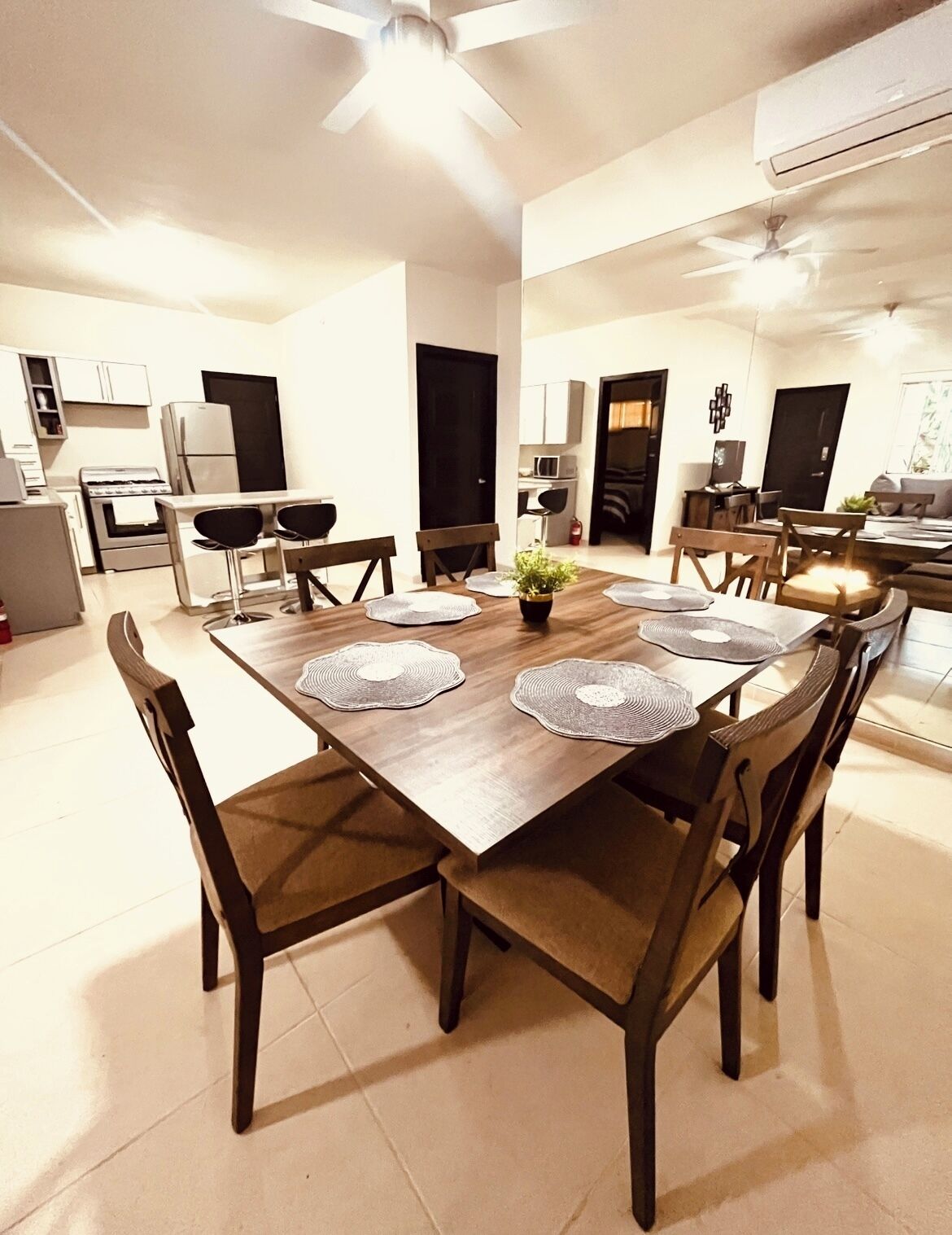 Un vaste espace dédié à la salle à manger, avec une table et des chaises en bois, un ventilateur de plafond et un appareil de climatisation.