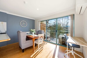 A modern room with a dining table, chairs, a clock, and a large sliding glass door leading to an outdoor area. - Stylish 2-Bed Apartment in Kingston (Kingston)