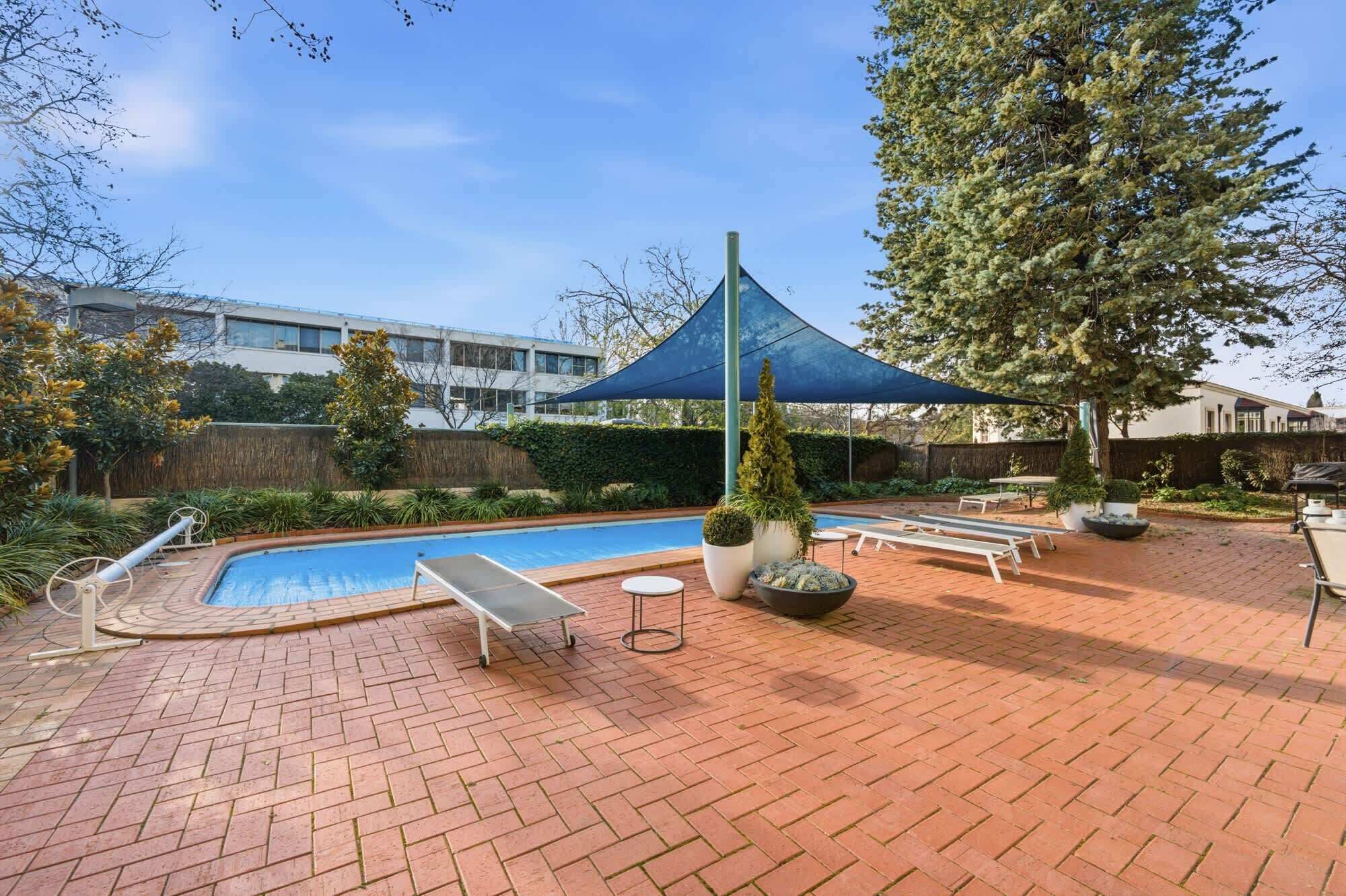 Uma área de piscina com espreguiçadeiras e um guarda-sol.