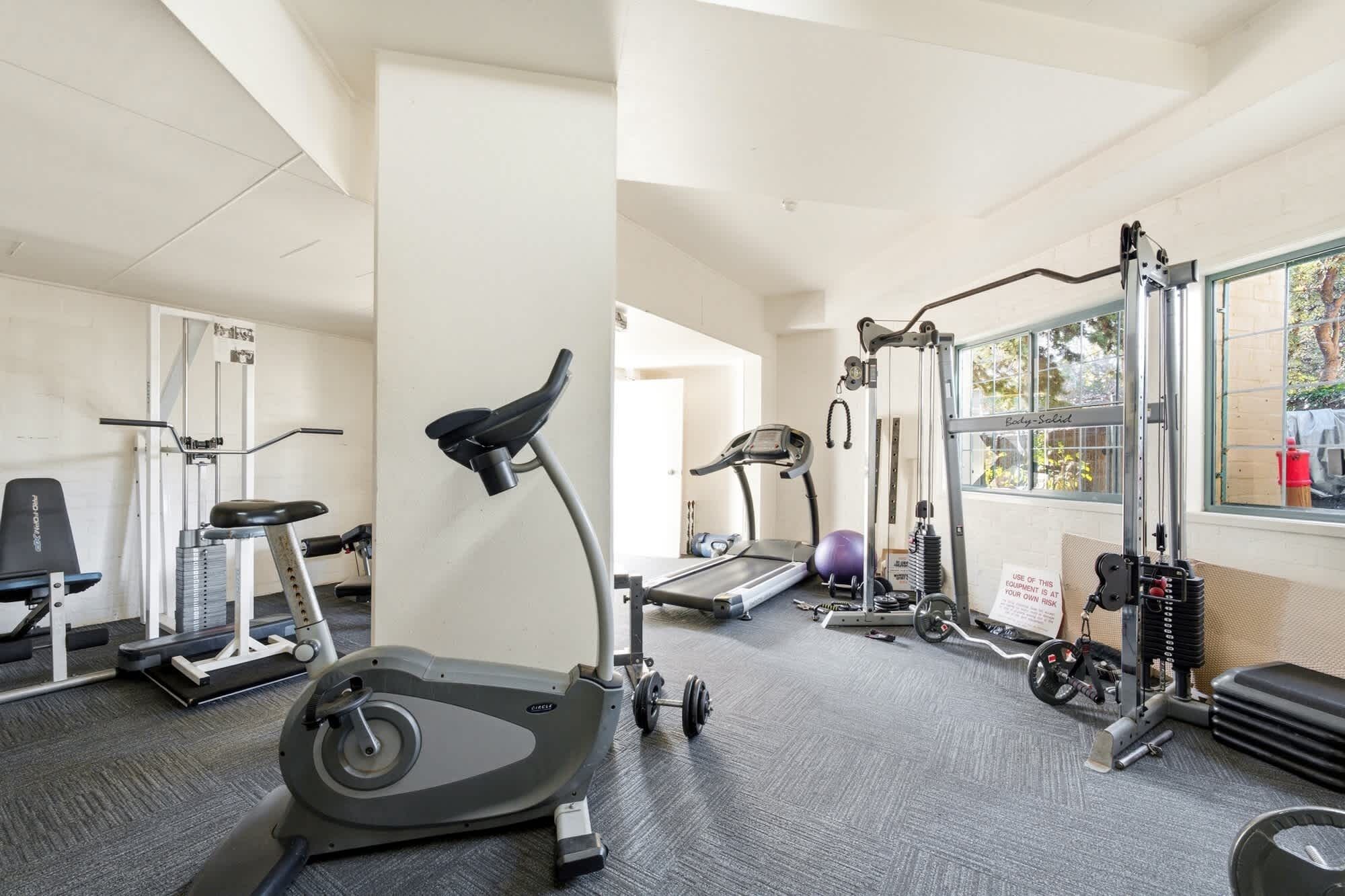 A gym with cardio equipment, weight machines, and a window with a view.