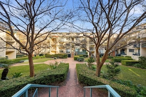 A courtyard with a central pathway, surrounded by trees and a building with multiple balconies. - Stylish 2-Bed Apartment in Kingston (Kingston)