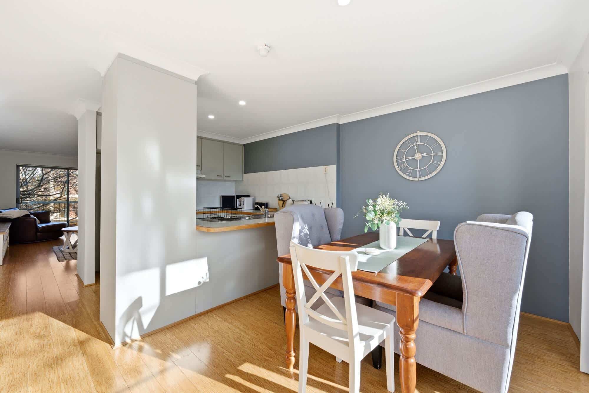 Een moderne woonkamer met een eettafel, een bank en een keuken op de achtergrond.