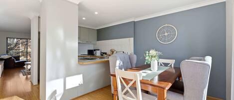 Una sala de estar moderna con una mesa de comedor, un sofá y una cocina al fondo.