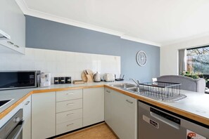 A compact kitchen with a microwave, toaster, sink, and a dishwasher. - Stylish 2-Bed Apartment in Kingston (Kingston)