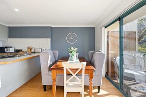 A modern kitchen with a dining area, a clock on the wall, and a view through a glass door. - Stylish 2-Bed Apartment in Kingston (Kingston)