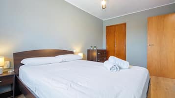 A hotel room with a bed, bedside lamps, a wooden wardrobe, and a ceiling fan.