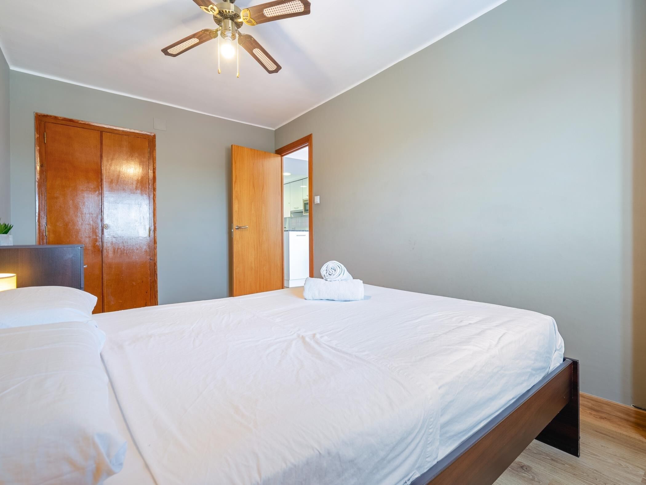 Un dormitorio con cama, ventilador de techo y puerta que da a un baño.