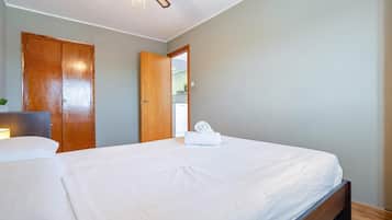 Un dormitorio con cama, ventilador de techo y puerta que da a un baño.