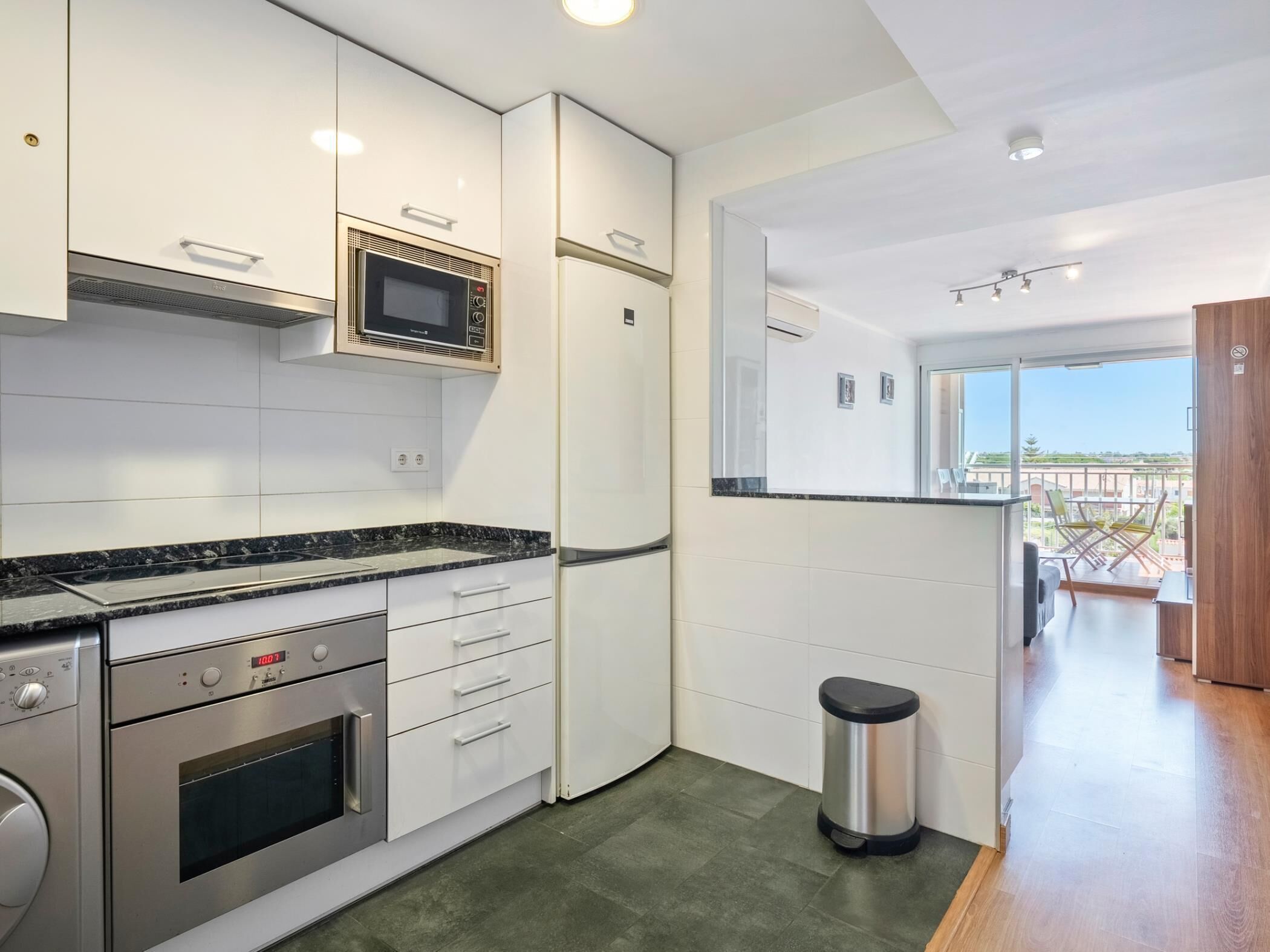Una cocina moderna con microondas incorporado, horno y electrodomésticos de acero inoxidable.