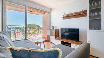 Una sala de estar moderna con un televisor de pantalla plana grande, un sofá, una mesita y un balcón con vistas.
