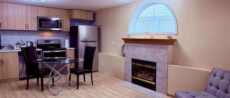 Un espacio habitable compacto con kitchenette, comedor, chimenea y asientos.