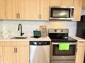 Une cuisine moderne équipée d’appareils électroménagers en acier inoxydable, notamment un four à micro-ondes, un four et un lave-vaisselle.