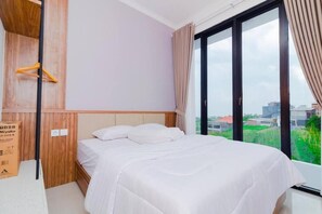Un dormitorio con cama, paneles de madera, una ventana con cortinas y vista a la ciudad.