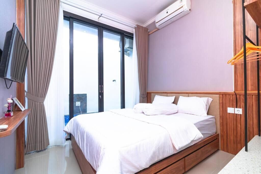 Quarto de hotel com uma cama, televisão, janela com cortinas e ar condicionado.