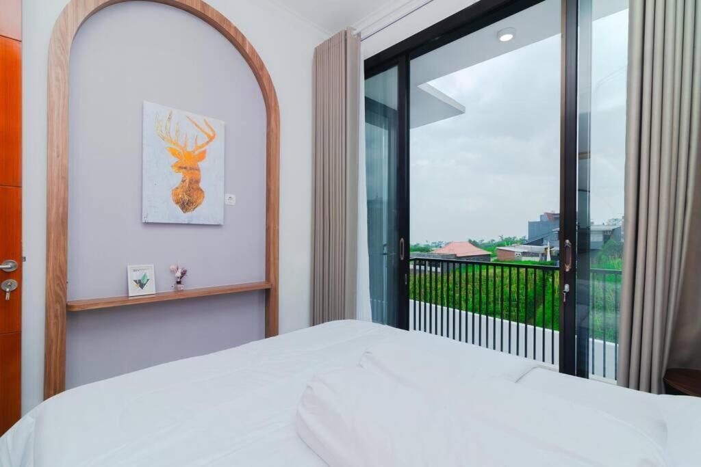 Een hotelkamer met een bed, een inlijsting kunstwerk aan de muur, een raam met uitzicht en een deur met houten frame.