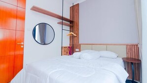 A hotel room with a bed, a wardrobe, a mirror, a hanging light, and a small table. - Cozzy Villa Ree (batu)