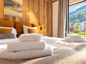 Een hotelkamer met een bed, kussens, een deken en uitzicht op een berglandschap.