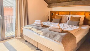 Ein Schlafzimmer mit einem großen Bett, Holzbalkendecke und Blick ins Freie.
