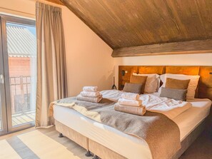Ein Schlafzimmer mit einem großen Bett, Holzbalkendecke und Blick ins Freie.