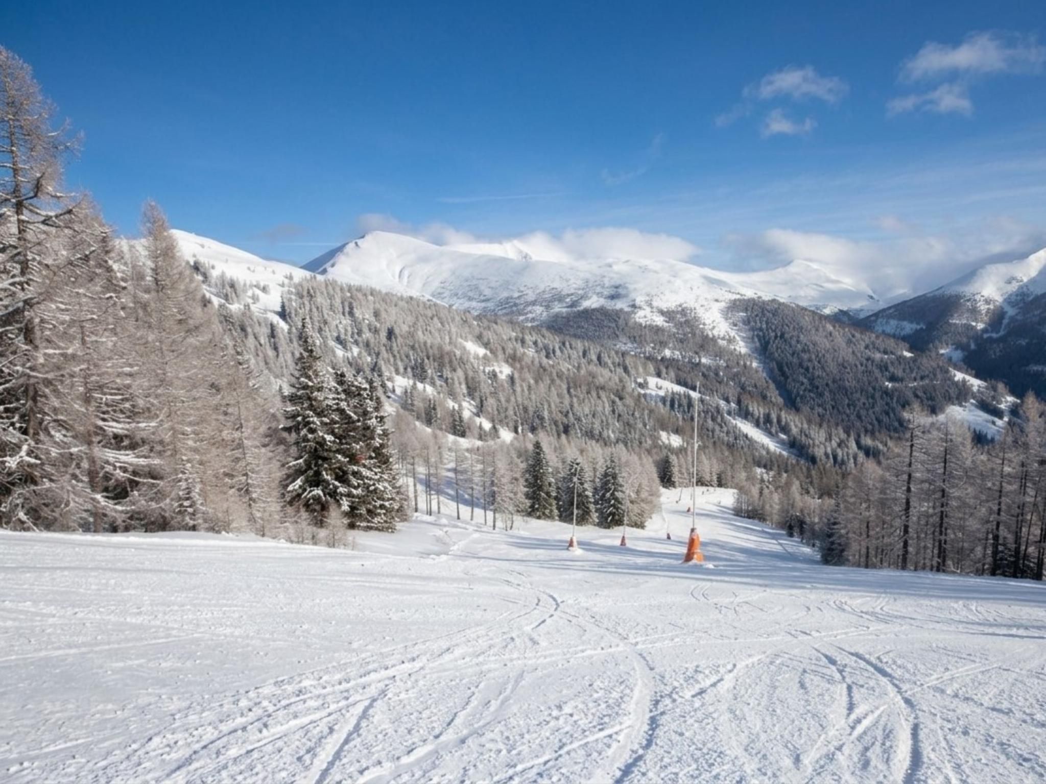 A snowy mountain landscape with ski tracks and a clear sky.