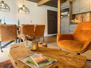 Ein modernes Wohnzimmer mit Couch, Holztisch und Essbereich, gedeckt für eine Mahlzeit.