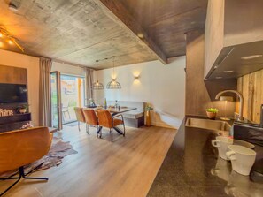 A modern kitchen with a dark countertop, a dining area with a wooden table and chairs, and a large window providing natural light. - Apartment by lake Afritzer See in the Alps (Afritz am See)