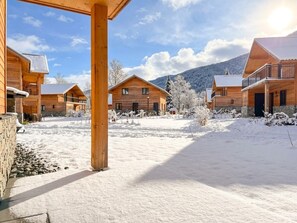 A wooden lodge with multiple cabins, a covered outdoor area, and a snowy landscape with mountains in the background. - Apartment by lake Afritzer See in the Alps (Afritz am See)