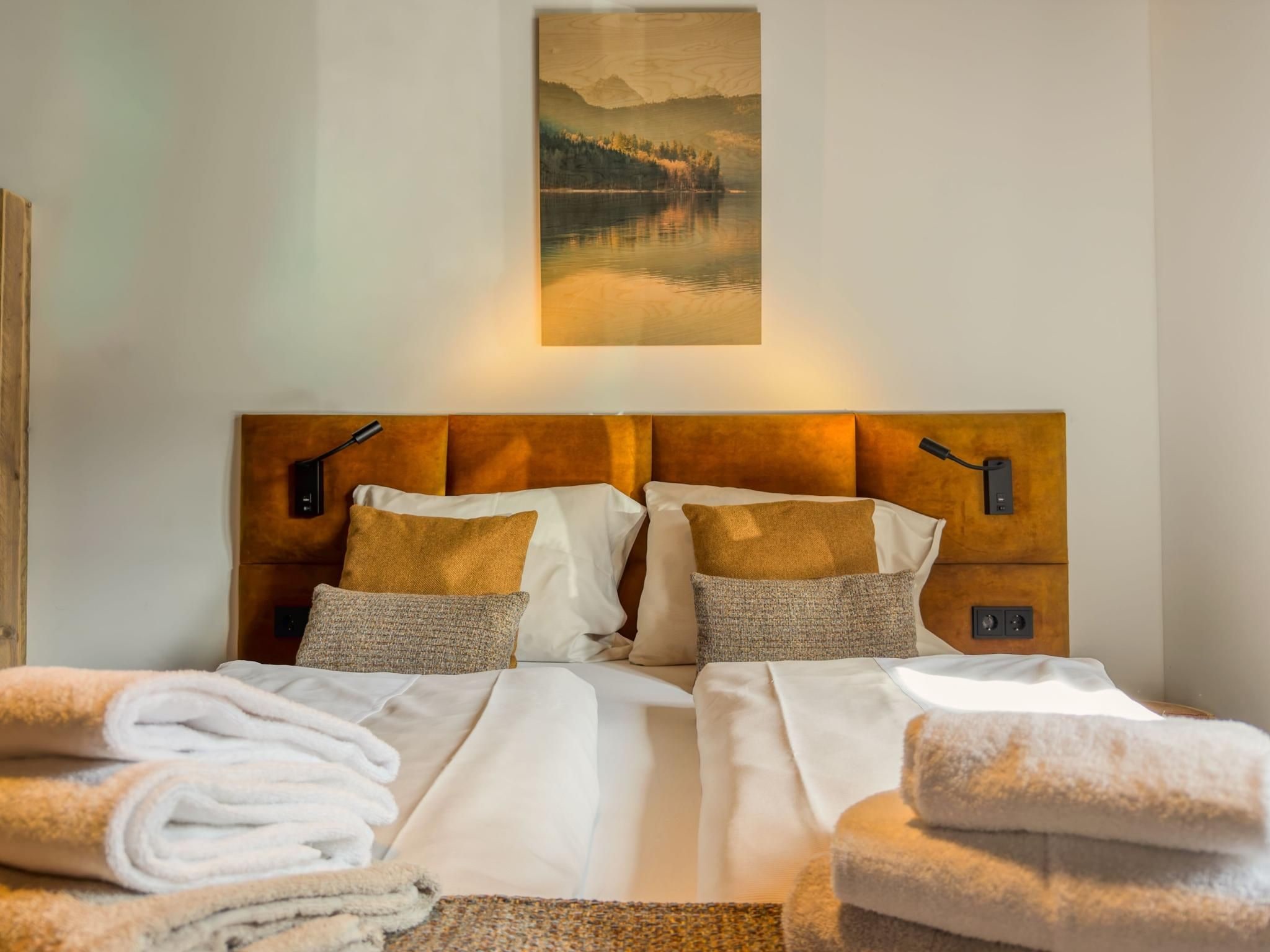 A hotel room with a large bed, two bedside tables, a headboard, and a painting above the bed.