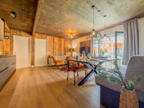 A modern kitchen with wooden walls, a dining area with a table and chairs, and a large window providing a view of the outside. - Apartment by lake Afritzer See in the Alps (Afritz am See)