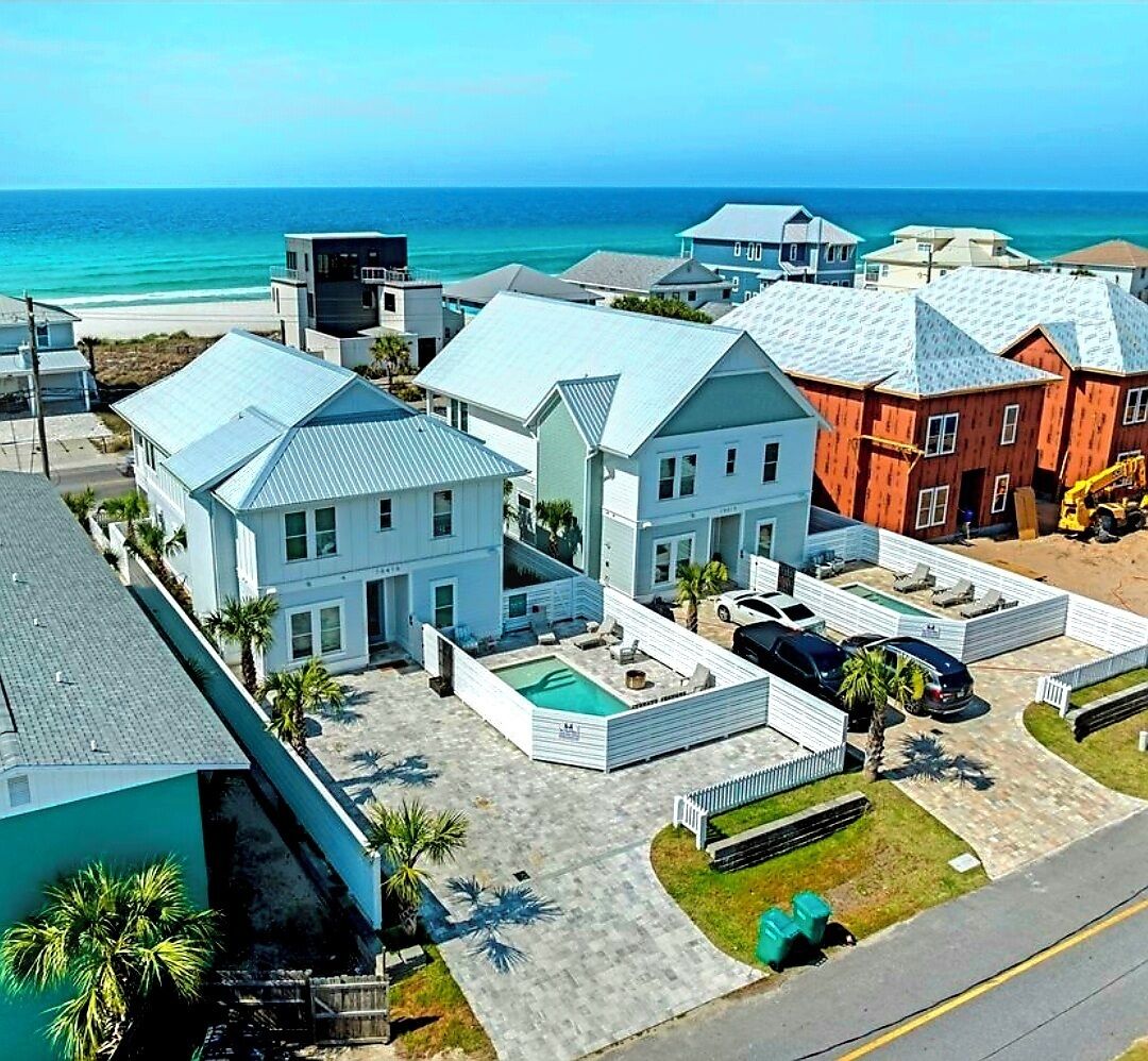 A coastal residential area with houses, a swimming pool, and a view of the ocean.