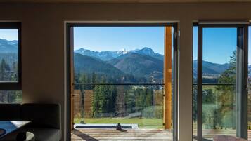 A room with a large sliding glass door leading to a balcony with a mountain view.