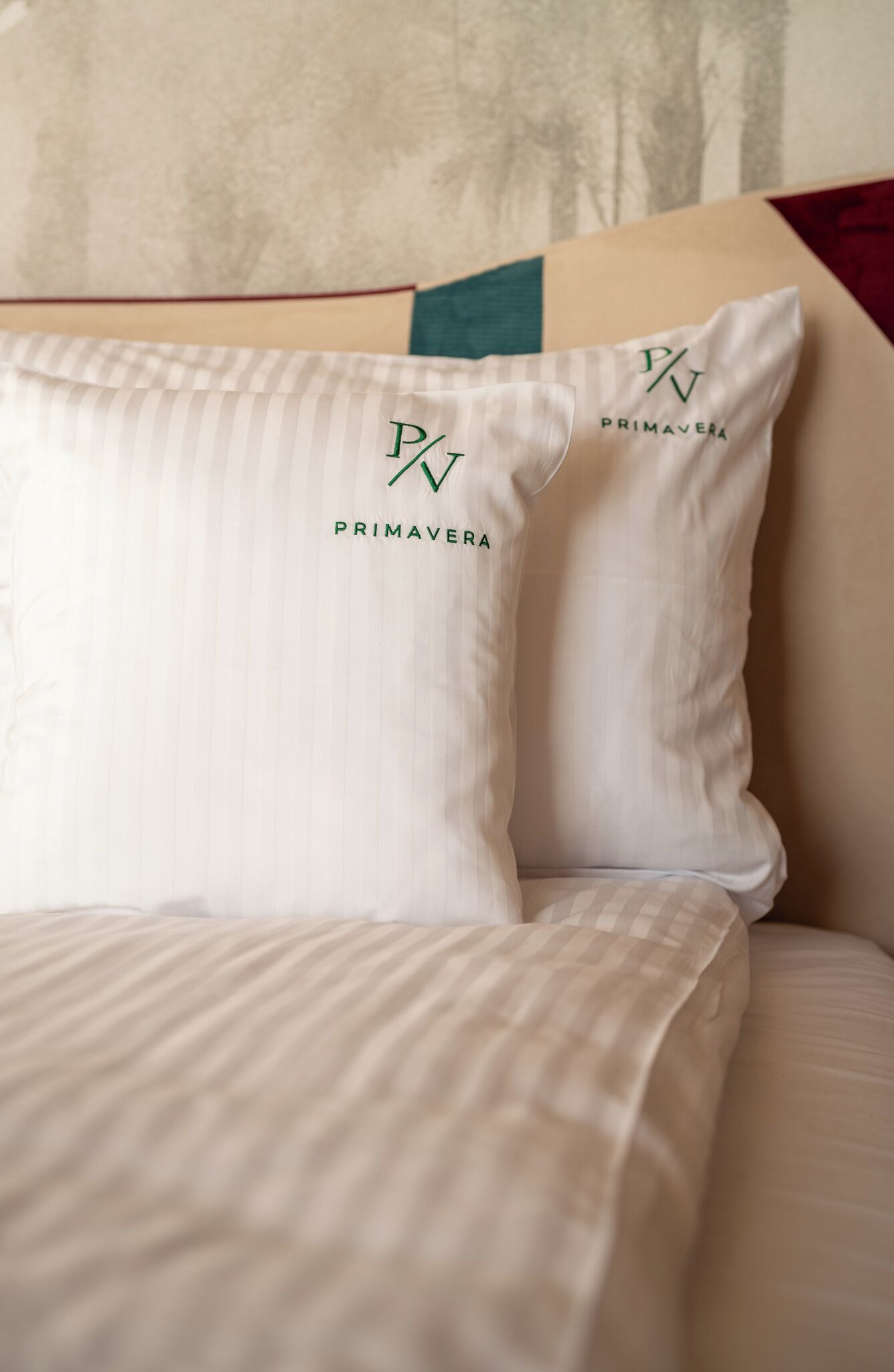 A bed with striped bedding and two pillows with a logo and text.