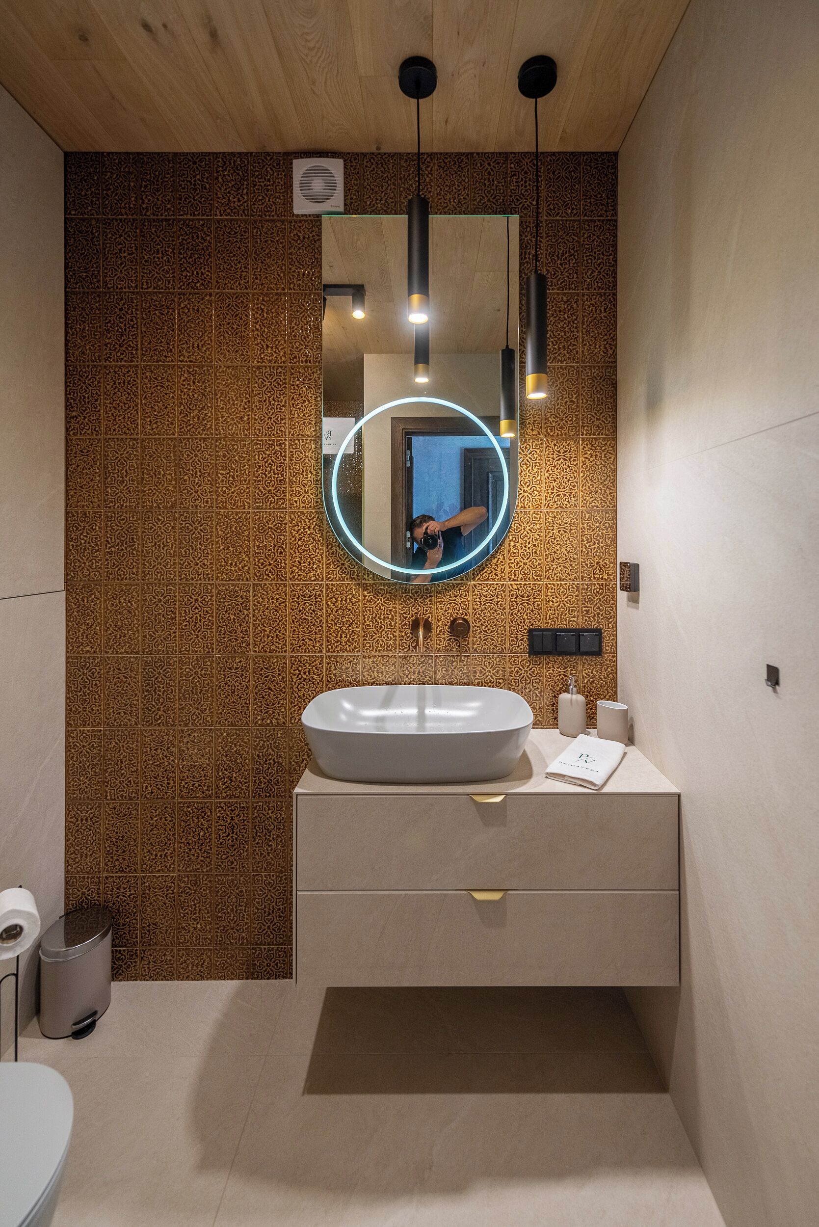 A modern bathroom with a large mirror, a sink, and a toilet.