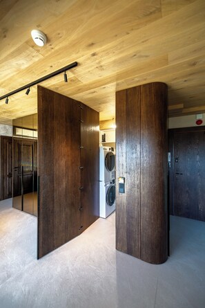 A modern interior with wooden beams, a large mirror, and a washing machine. - Apartament Primavera (zakopane)