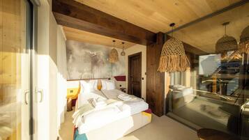 A modern bedroom with a large bed, wooden ceiling beams, and a glass door leading to a balcony.