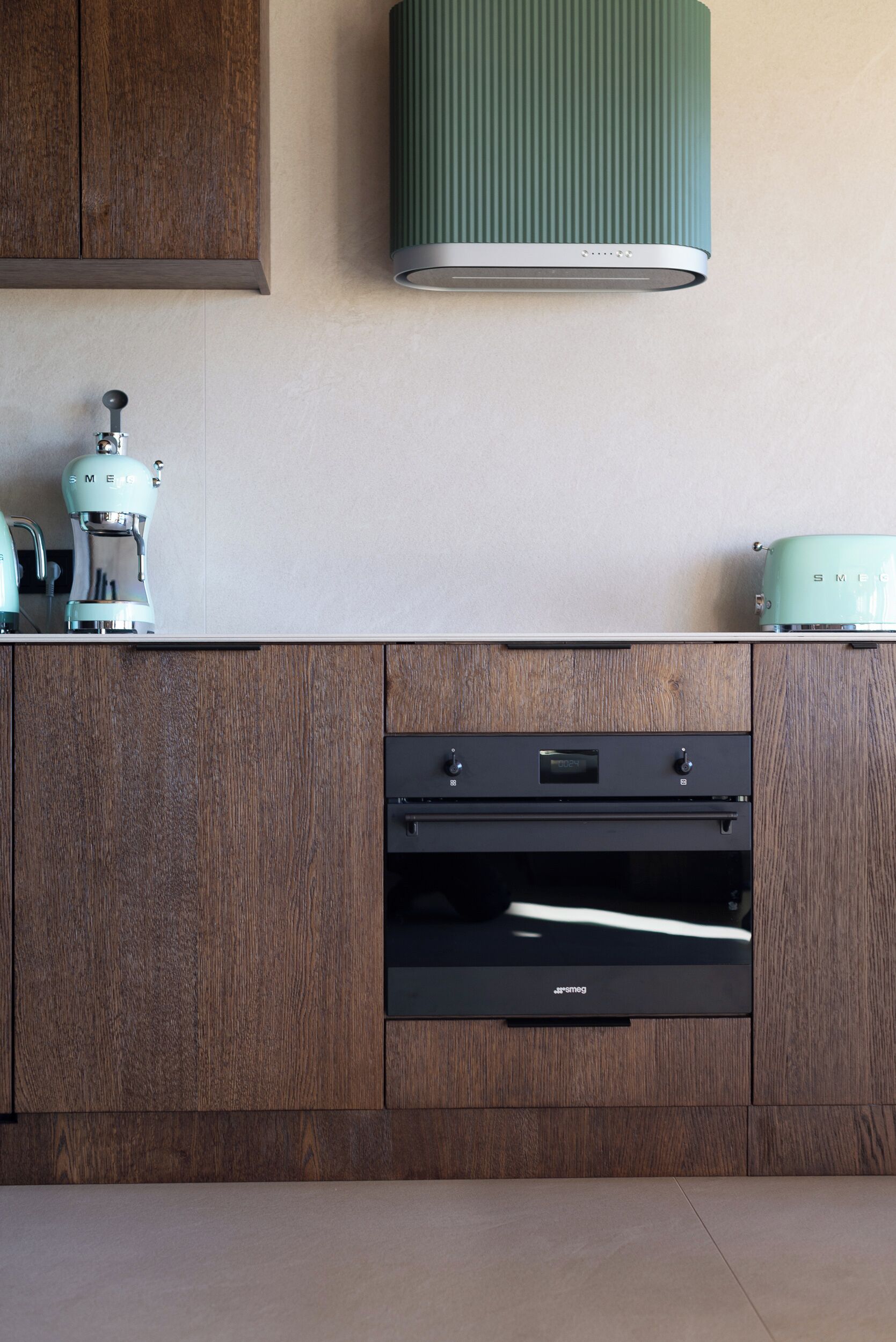 A kitchen with wooden cabinets, a built-in oven, and a green wall-mounted light fixture.